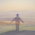 Eine halbtransparente Silhouette einer Person, die mit leicht ausgestreckten Armen vor einer weichen, pastellfarbenen Landschaft mit sanften Hügeln und einem dunstigen, verträumten Himmel steht und ein Gefühl von Freiheit vermittelt.